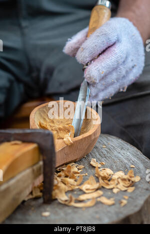 Craftsman demonstrates the process of making wooden spoons handmade using tools. National crafts concept. Stock Photo