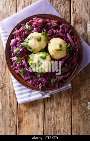 German food knodel potato dumplings and stewed red cabbage close-up on a plate on the table.Vertical top view from above Stock Photo