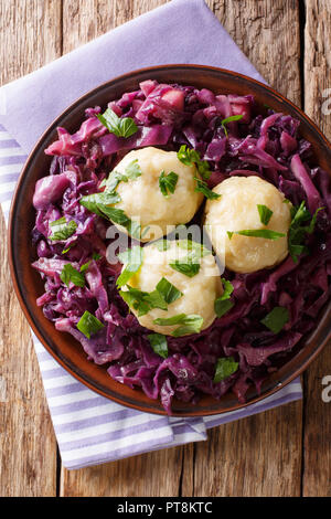 Freshly cooked potato dumplings served with stewed red cabbage close-up on a plate on the table. Vertical top view from above Stock Photo