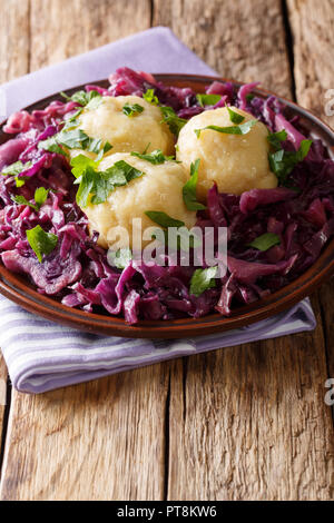 Delicious potato dumplings with stewed red cabbage close-up on a plate on the table. vertical Stock Photo