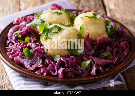 Freshly cooked potato dumplings served with stewed red cabbage close-up on a plate on the table. horizontal Stock Photo