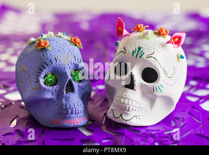 Purple and white Sugar skulls,  Day of the dead altar with Purple papel picado (tissue paper cut outs) as decoration. Stock Photo