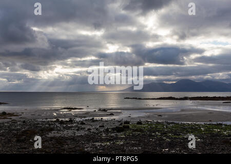 Sun rays bursting through clouds over Irish Seaa and Mourne Mountains as seen from Rossglass Beach, County Down, N.Ireland. Stock Photo