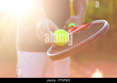 A tennis player prepares to serve a tennis ball during a match Stock Photo