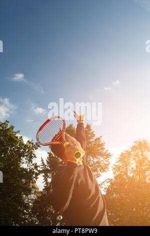 A tennis player prepares to serve a tennis ball during a match Stock Photo