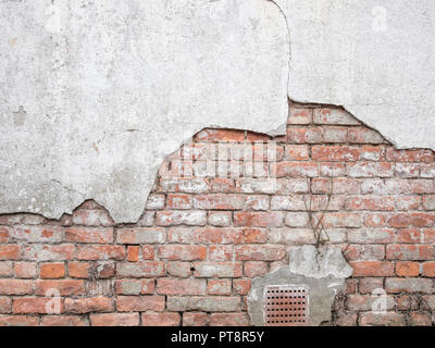 Weathered old brick wall in need of repair as cement render falls away. Exposed brickwork, metaphor exposed, hit a brick wall, UK construction sector. Stock Photo