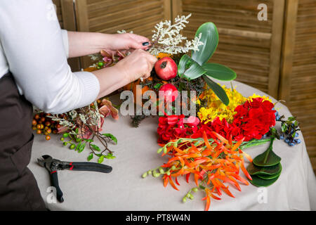 Florist at work: How to make a Thanksgiving centerpiece with big pumpkin and bouquet of flowers. Step by step, tutorial. Stock Photo