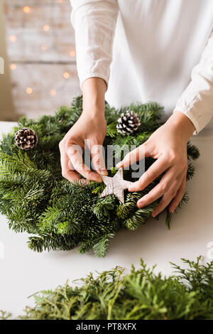 A unrecognizable woman decorating a christmas wreath. Stock Photo