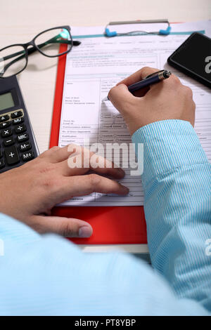 Man is filling form with pen. Picture of form on the clipboard. Stock Photo