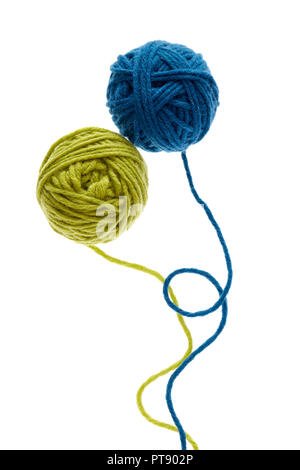 Blue and green woolen balls over white background. Two balls of wool partially unrolled. Stock Photo