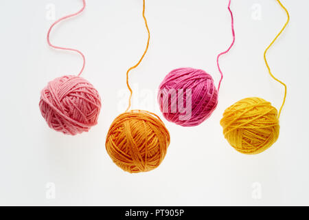 Colorful woolen balls over white background. Balls of wool partially unrolled. Stock Photo