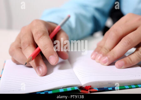Man holding pencil in hand with notebook on the table. Stock Photo