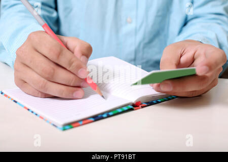 Man is writing address on notebook with looking card. Stock Photo