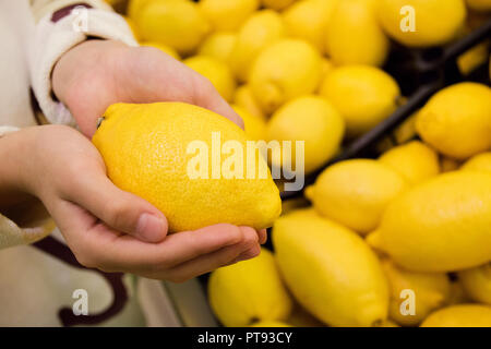Vegetarians and fresh fruit and vegetables on the nature of the theme: human hand holding a lemon. Stock Photo
