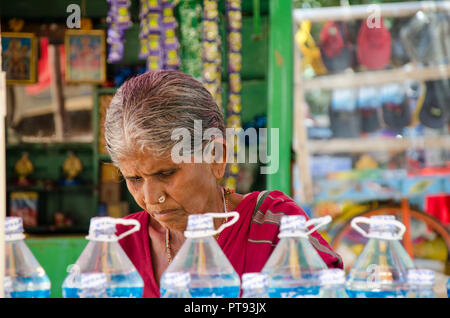 Close-up portrait of a local elderly woman working in her stall selling water bottles and other items at Hampi, Karnataka, India. Stock Photo