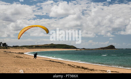 Yellow paraglider taking off a beach near Saint Malo (France) on a cloudy day in summer Stock Photo