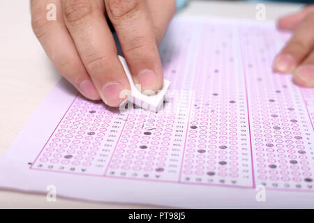 Man hand is erasing filled OMR sheet with eraser. Stock Photo