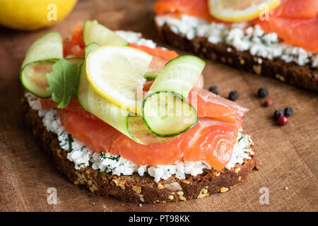Rye toast with smoked salmon, cucumber and cream cheese on rustic wood background, closeup view Stock Photo