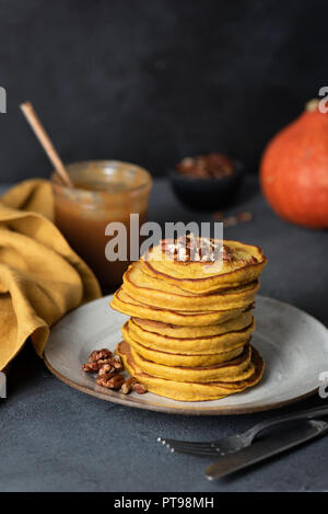Stack of tasty pumpkin pancakes with pecans and salted caramel sauce. Selective focus Stock Photo