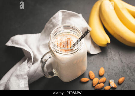 Banana smoothie or protein shake in drinking jar topped with cinnamon. Toned image, selective focus Stock Photo