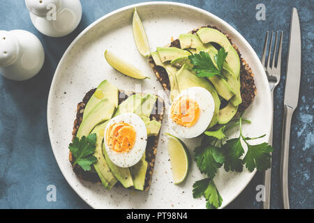 Healthy avocado toasts with boiled egg on a plate. Top view, toned image Stock Photo