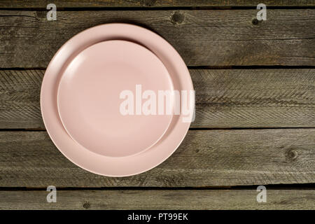 Empty pink plates on rustic wooden background Stock Photo