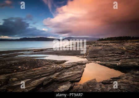 Sunset time by Flatholmen beach in Muruvik. Amazing sky and clouds colours. Shores of Trondheimsfjorden, Norway. Stock Photo