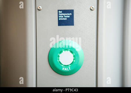 Close-up. Stop button in the train. The inscription in German language is translated - STOP. Above the inscription is translated - Continue to press the button. Stock Photo