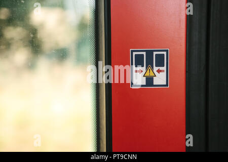 Close-up on the door in the train warning sign about the danger when closing the door. Stock Photo