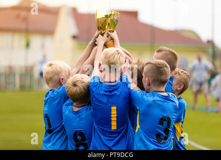 Young Soccer Players Holding Trophy. Boys Celebrating Soccer Football Championship. Winning team of sport tournament for kids children teams. Stock Photo
