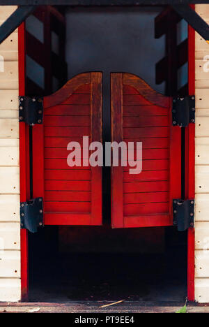Red closed Western Saloon doors on a white wooden wall on a bright sunny day Stock Photo