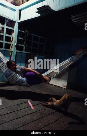 Macedonia, Amazonia / Colombia - MAR 15 2016: lady is resting in a hammock during the quiet evening in the middle of the rainforest Stock Photo
