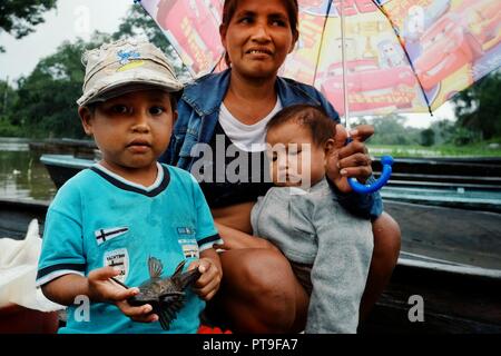 Macedonia, Amazonia / Colombia - MAR 15 2016: local family from a rainforest jungle village coming back from a fishing trip with cute kids in the rain Stock Photo