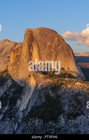 A close-up of Half Dome. Golden light from the sunset is cast upon the Mountain tops, while the moon is out. Image from Glacier Point, in early April. Stock Photo