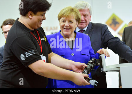 Darmstadt, Hessen, Germany. 08th Oct, 2018. German Chancellor Angela Merkel and Hesse's Prime Minister Volker Bouffier (r, both CDU), with the help of a student, operate the humanoid robot Johnny during a visit to the Technical University. During a demonstration, search and rescue robots from the 'Hector' team are used, which can, for example, search autonomously for buried people. Credit: Uwe Anspach/dpa/Alamy Live News Stock Photo