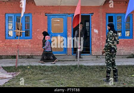 Residents walk to a polling station to vote during the first phase of local elections in Srinagar, Indian administered Kashmir. Amid tight security arrangements, voting began for the first phase of the urban local bodies (ULB) elections in Jammu and Kashmir on 08 October. Stock Photo