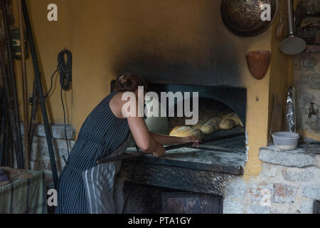 Woman baker baking bread in old style oven Stock Photo