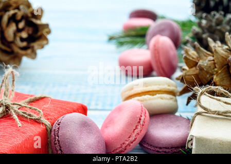Sweet macarons, gifts and fir cones and on a blue background. Christmas background. New Year's composition. Stock Photo