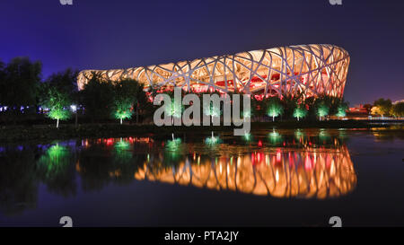 Bird's nest at night time mirrored in a pond. the Bird's Nest is an Olympic stadium in Beijing, China. Stock Photo