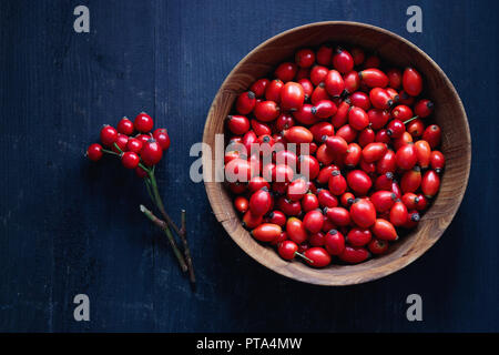 Freshly picked rose hips. Wooden bowl of rose hip or rosehip, commonly known as the dog rose (Rosa canina). Stock Photo