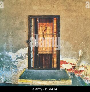 Walled door entry of abandoned house. Broken iron bars over door hole.  Old weathered brick wall fragment Stock Photo