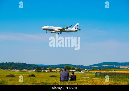 Happy Young Couple Watching Airplanes Near the Airport. a Woman Sitting on  a Suitcase Stock Image - Image of medical, flying: 185026513