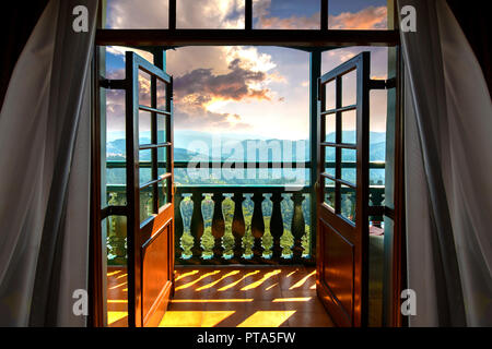 Light from the setting sun penetrating the clouds, falling on the balcony and entering the room as though calling the occupants to witness the mesmeri Stock Photo