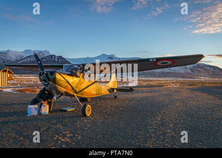 Pilot by small propeller airplane at sunset, Iceland Stock Photo