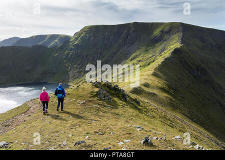 Two Walkers Heading Towards Helvellyn via Swirral Edge From Catstye Cam, Lake District, Cumbria, UK Stock Photo