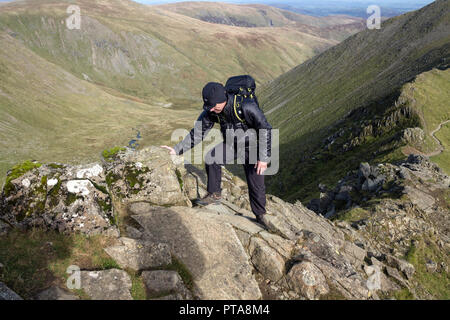 Walker Scrambling on Swirral Edge, Helvellyn, Lake District, Cumbria, UK. Stock Photo