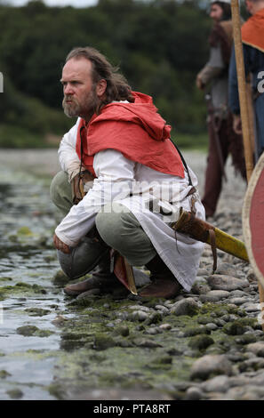 A Viking warrior takes a rest beside a river, part of a viking reenactment group which takes part in historical shows. Stock Photo