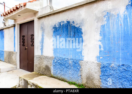 Blue & white painted house exterior wall with splashed paint & metal door in Central America Stock Photo
