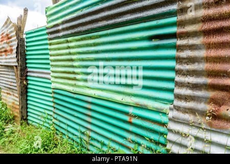 Close up of old green painted rusty corrugated iron fence Stock Photo