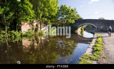 Leeds, England - June 30, 2015: A cyclist rides on the towpath alongside the Leeds and Liverpool Canal in West Yorkshire. Stock Photo